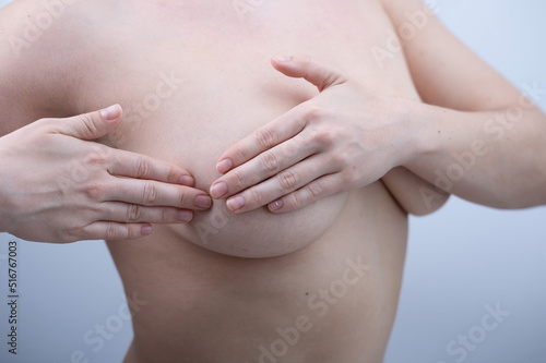 Caucasian woman self checks for breast cancer on white background. 