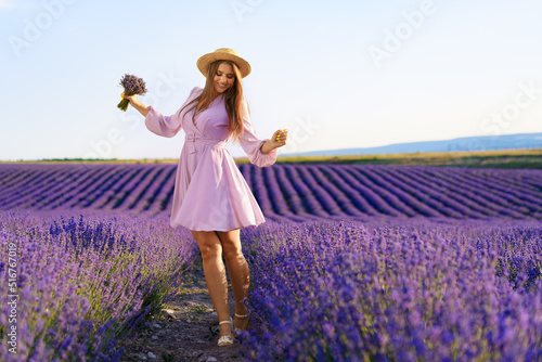 Fototapeta Naklejka Na Ścianę i Meble -  Young woman in a lilac dress walking in a lavender field