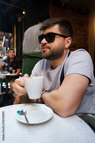 Handsome man drinking coffee in outdoor cafe
