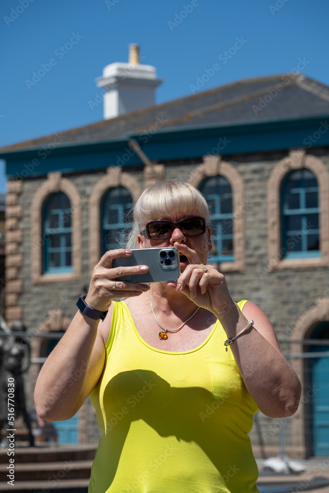 Mature woman on holiday taking photographs on a mobile phone.
