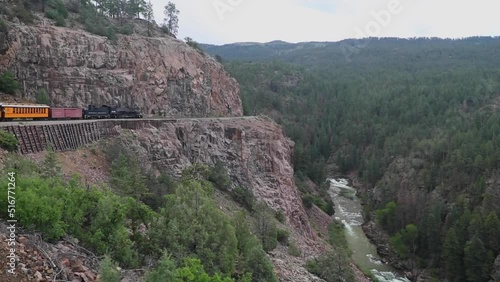 Antique train on the side of a cliff next to the anima river