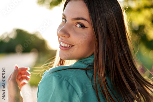 Portrait of young woman in green shirt smiling in a park