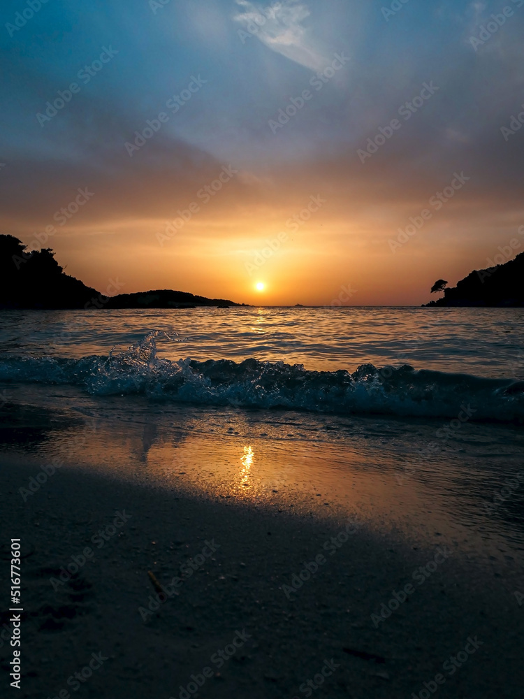 Sunset on a sandy beach with beautiful sea waves