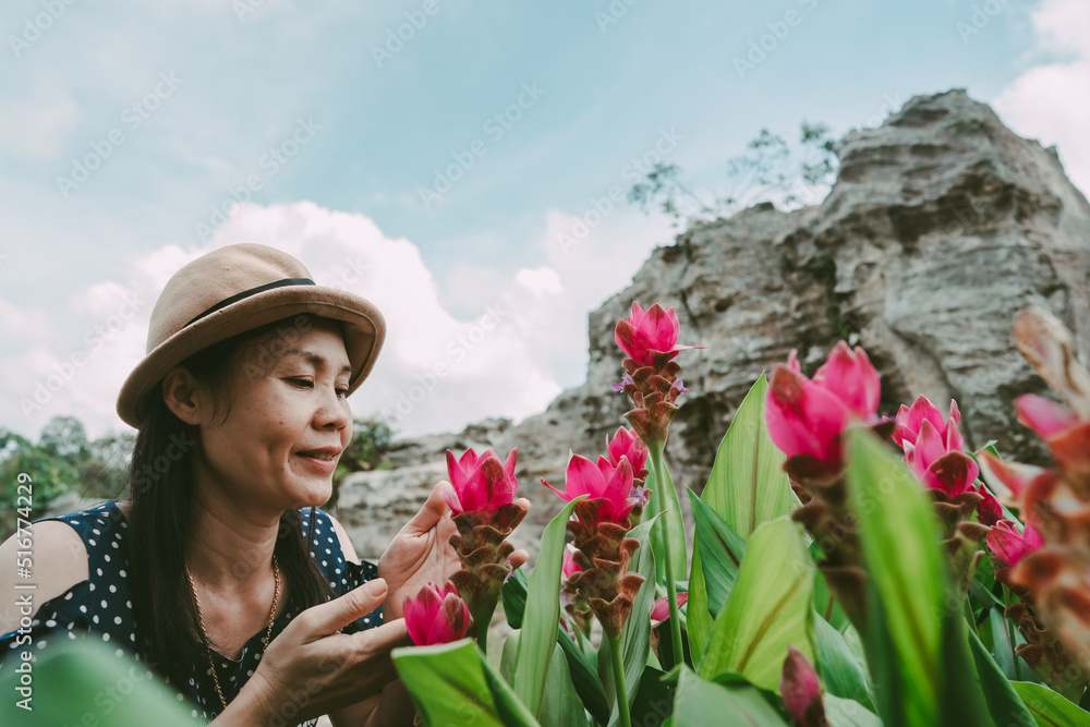 Women looking flower in garden on stone and sky background