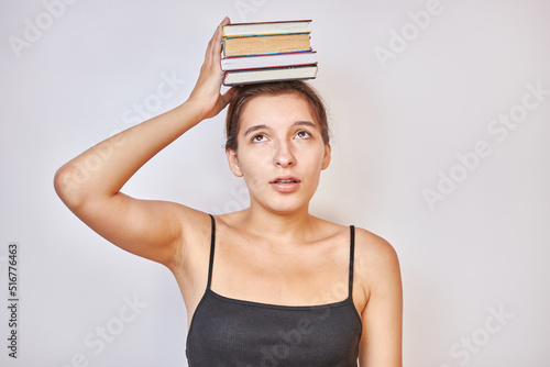 The girl holds books on her head. Hard training concept.