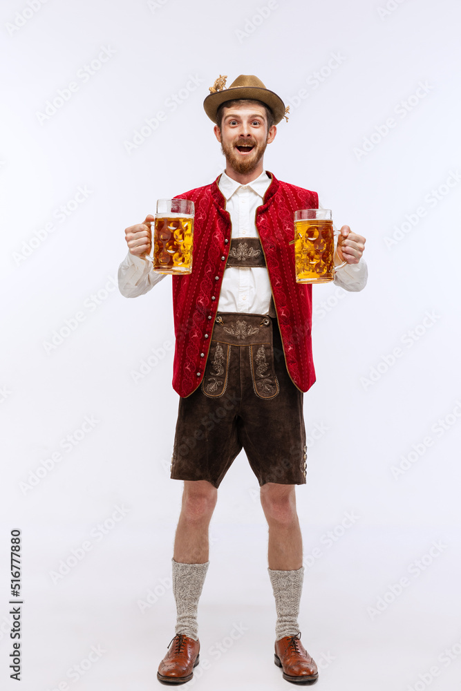Portrait of Oktoberfest young emotional man in hat, wearing the traditional Bavarian clothes, holding beer mug. Alcohol, traditions, holidays, festival concept.