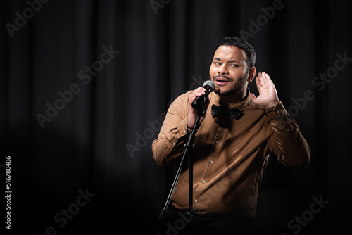 Canvastavla indian comedian listening during stand up comedy show on black.
