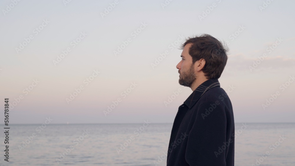 young man with overcoat looks at the horizon at sunset next to the river young man with overcoat looks at the horizon at sunset next to the river