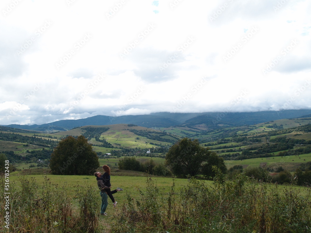 A couple in love in a front of a wonderful picturesque wiew in the mountains. A trip together through the national park