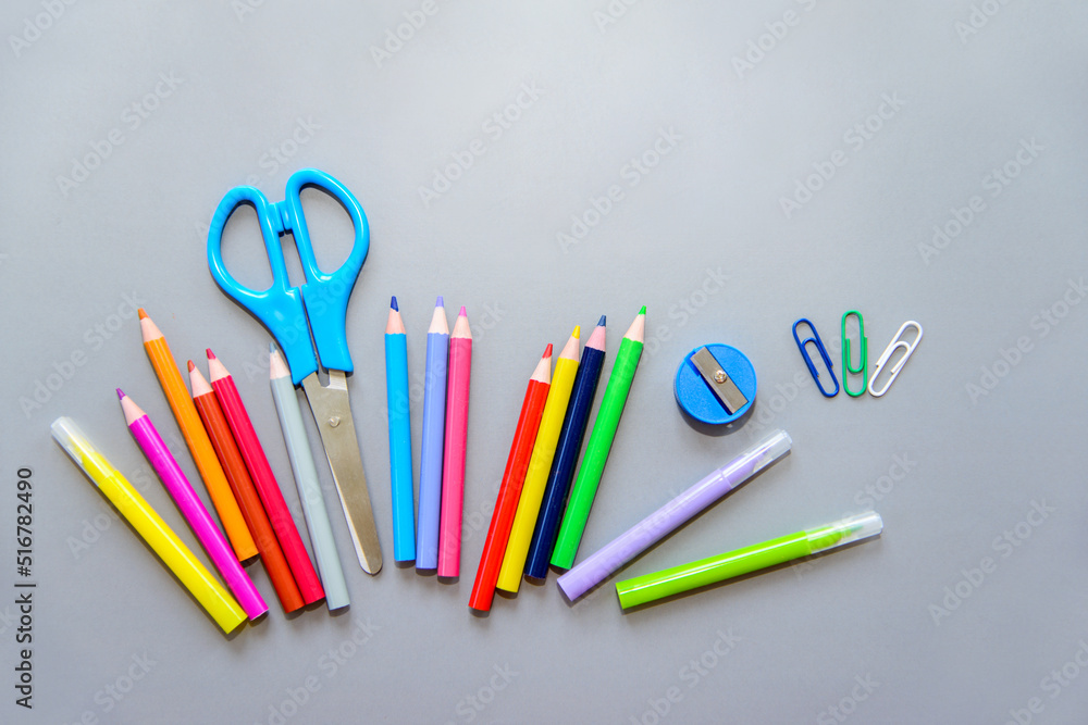 school supplies on a gray background. Colored pencils, felt-tip pens, eraser, paper clip, scissors, sharpener. Back to school