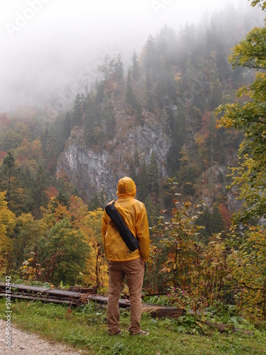  man wearing yellow jacket standing by the mountain and looking at the distance