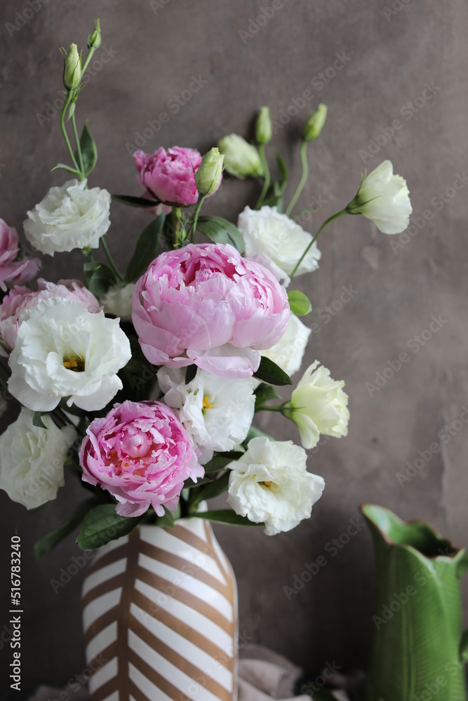 A beautiful bouquet of white lisianthus and pink peonies in a vase on a table with a linen napkin. Seasonal summer flowers. A beautiful bouquet of white lisianthus and pink peonies in a vase on a table with a linen napkin. Seasonal summer flowers.