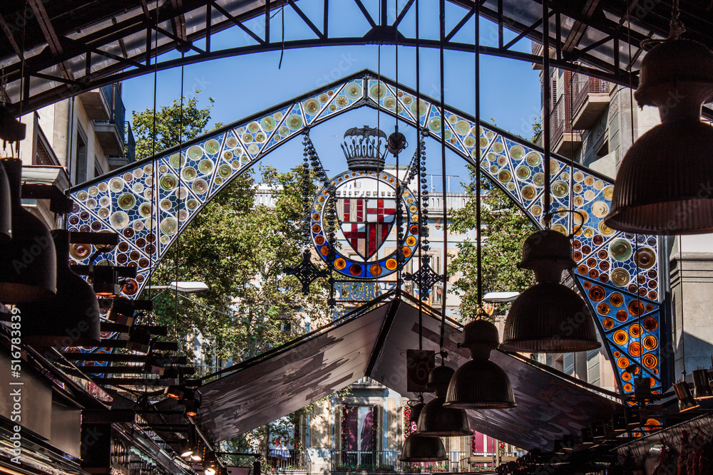Indoor detail of the famous Food Market (La Boqueria) in the old town of Barcelona, Catalonia, Spain, Europe. Colorful patterns and ornaments on glass. Grand iron entrance the way up the Las Ramblas. - obrazy, fototapety, plakaty 