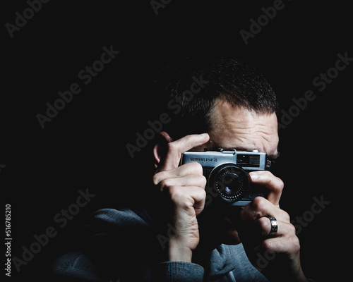 A man holds a vintage camera and takes photographs