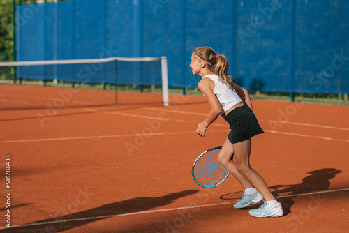 Young professional sportswoman playing tennis on sport court.