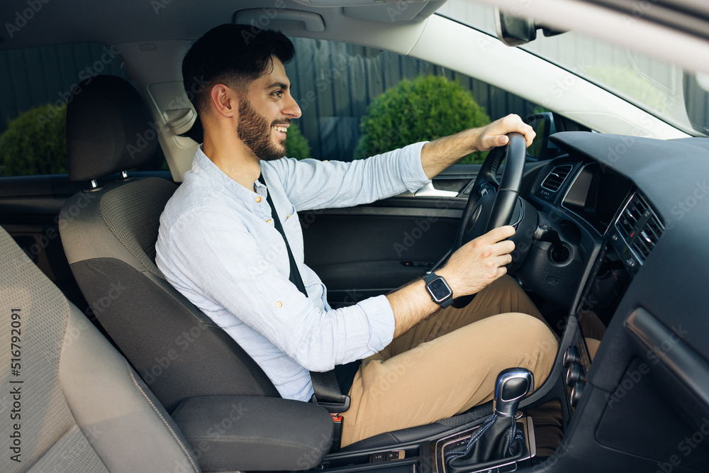 Handsome bearded man driving electric car commuting to work. Confident man driving sitting in the car at sunset. Look around. Automobile businessman traffic transportation work city Handsome bearded man driving electric car commuting to work. Confident man driving sitting in the car at sunset. Look around. Automobile businessman traffic transportation work city