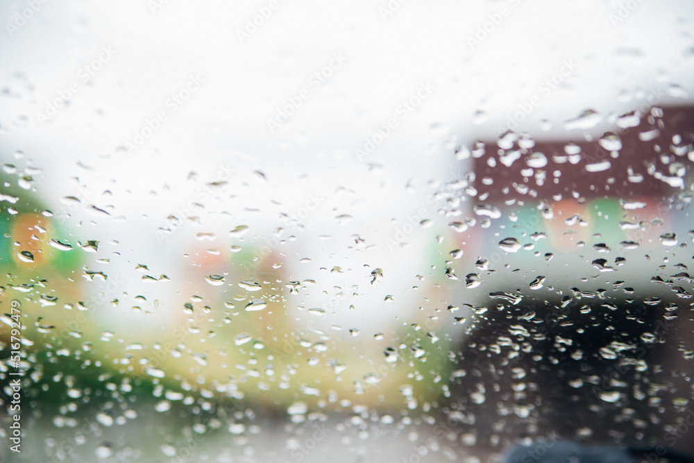 Close-up of raindrops on transparent glass.Blurred background of silhouette landscape.The texture of wet glass. Abstract background.