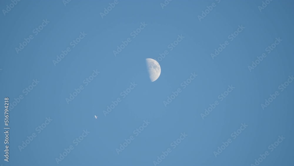 A plane flying high against the backdrop of a clear blue sky. Passes remarkably close to the half moon, travel concept, spirit of summer vibes, journey of adventure and wanderlust. A plane flying high against the backdrop of a clear blue sky. Passes remarkably close to the half moon, travel concept, spirit of summer vibes, journey of adventure and wanderlust.