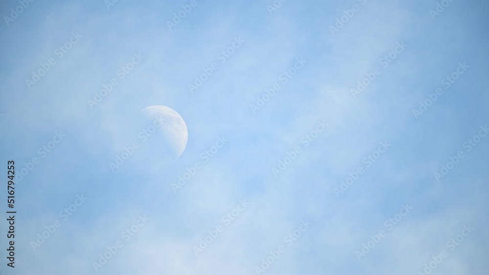 Half moon against blue sky with moving clouds Half moon against blue sky with moving clouds