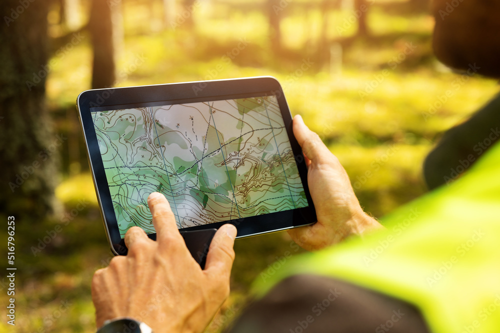 surveyor working with forest topography map in digital tablet. land surveying - obrazy, fototapety, plakaty 