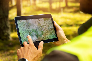 Foto auf Acrylglas Gelb vermesser, der mit der waldtopografiekarte in einem digitalen tablet arbeitet. Landvermessung  © ronstik