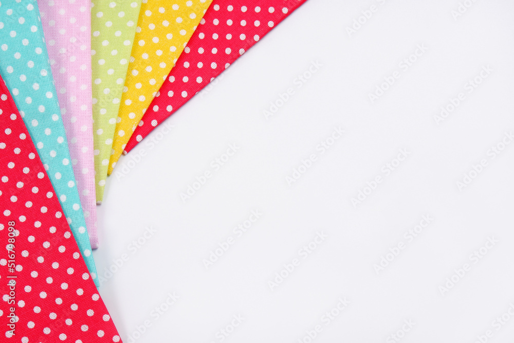 Bright multicolored patches of polka dot fabric laid out in an arc on a white background.The concept of manual labor, a workshop for sewing and repairing clothes, a sale in a fabric store.Copyspace