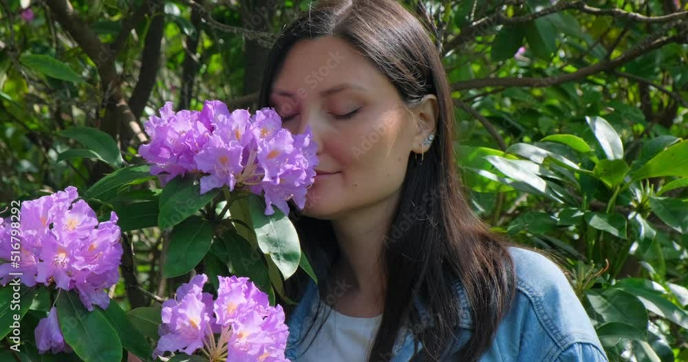 Female Smelling Lilac Flowers in the Garden. Happy Woman Looking at Blooming Tree. Female Smelling Lilac Flowers in the Garden. Happy Woman Looking at Blooming Tree.