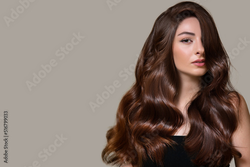 portrait of a beautiful brunette woman with curly wavy hair. on a gray background