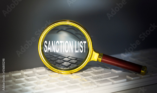 Bild auf Leinwand SANCTIONS LIST word concept on a magnifier on the keyboard