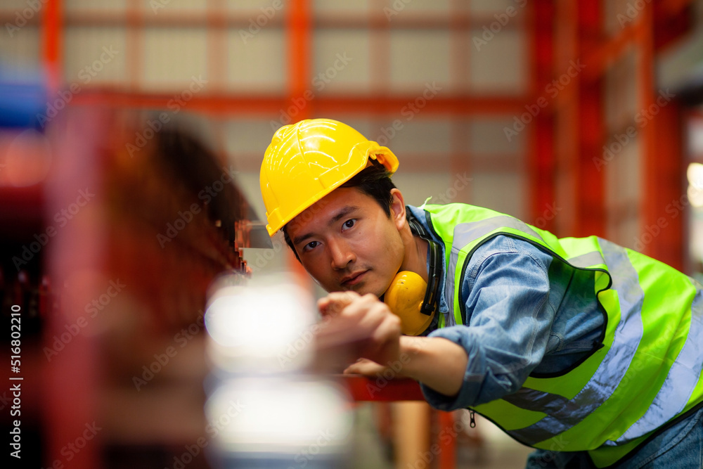 Portrait of an Asian male worker working in a modern industrial factory. Safety concept. Factory for manufacturing large machinery industry Portrait of an Asian male worker working in a modern industrial factory. Safety concept. Factory for manufacturing large machinery industry