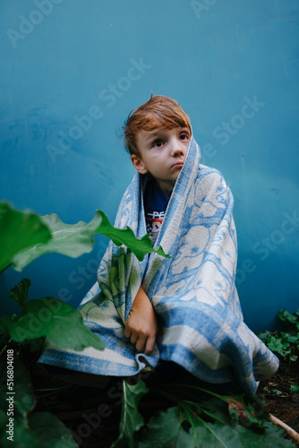 sad child with a crooked face under the covers