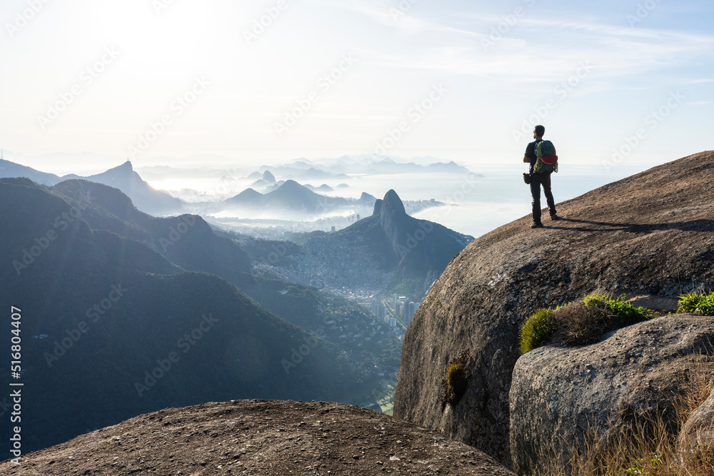 Climber enjoying beautiful view to city from rocky mountain top Climber enjoying beautiful view to city from rocky mountain top