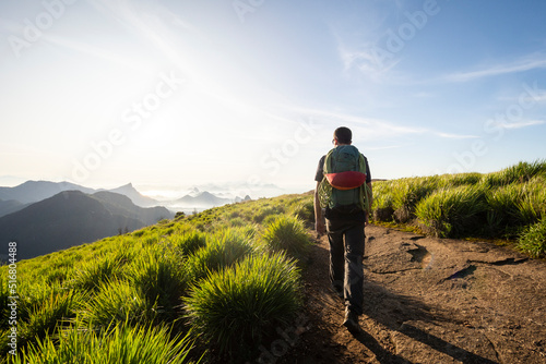 Beautiful view to man with backpack hiking on rainforest mountain top photo