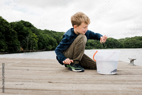 boy happily holding a crab that he caught whilst fishing on the dock