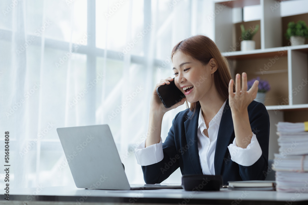 Asian woman talking on the phone, she is a salesperson in a startup company, she is calling customers to sell products and promotions. Concept of selling products through telephone channels. Asian woman talking on the phone, she is a salesperson in a startup company, she is calling customers to sell products and promotions. Concept of selling products through telephone channels.
