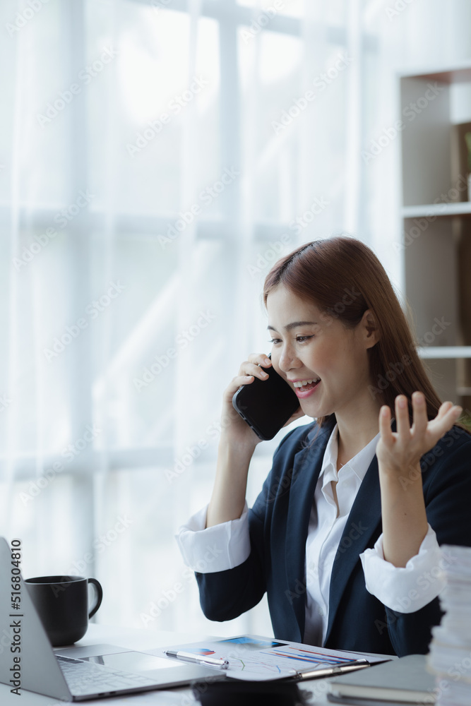 Asian woman talking on the phone, she is a salesperson in a startup company, she is calling customers to sell products and promotions. Concept of selling products through telephone channels.