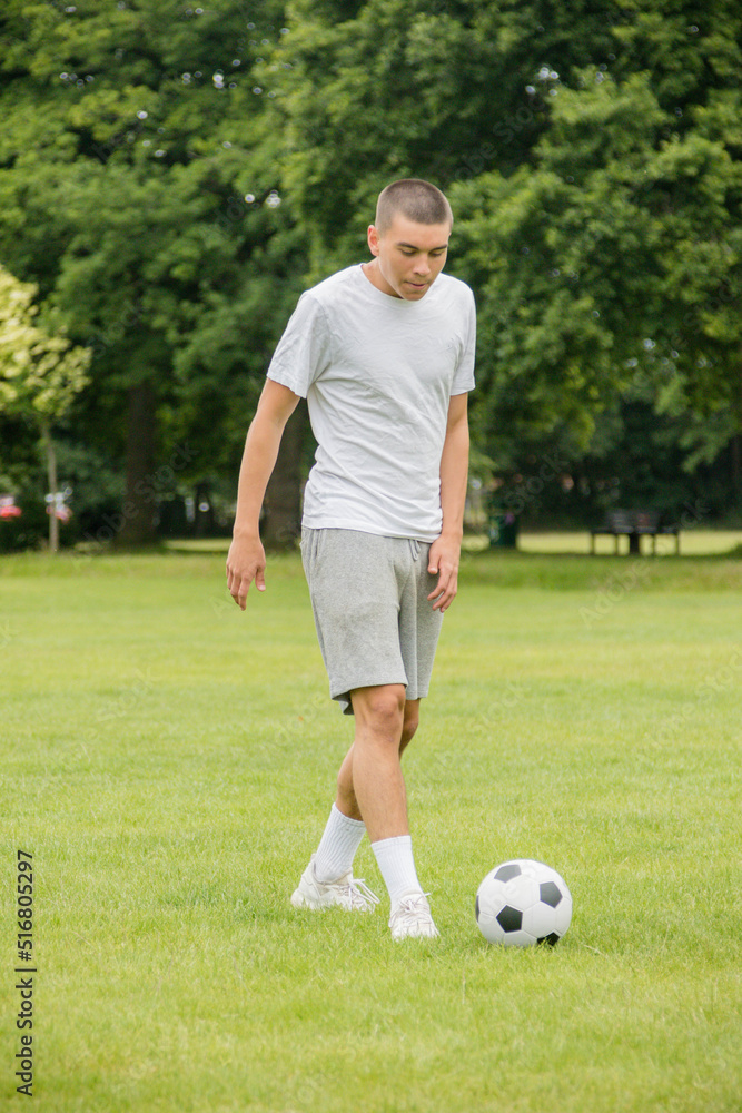 A Nineteen Year Old Teenage Boy Playing Football in A Public Park A Nineteen Year Old Teenage Boy Playing Football in A Public Park
