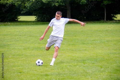 A Nineteen Year Old Teenage Boy Playing Football in A Public Park