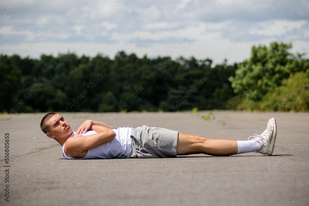 Obraz premium A Nineteen Year Old Teenage Boy Doing Leg Raises In A Public Park