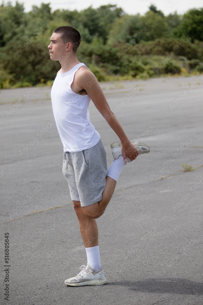 A Nineteen Year Old Teenage Boy Stretching In A Public Park A Nineteen Year Old Teenage Boy Stretching In A Public Park