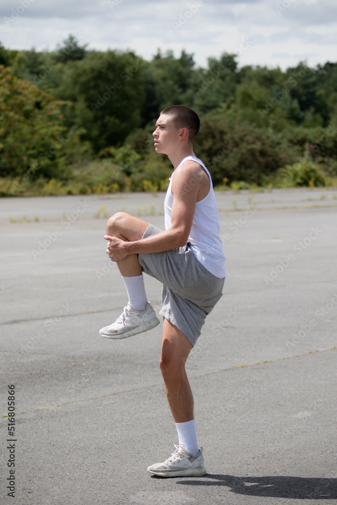 A Nineteen Year Old Teenage Boy Stretching In A Public Park A Nineteen Year Old Teenage Boy Stretching In A Public Park