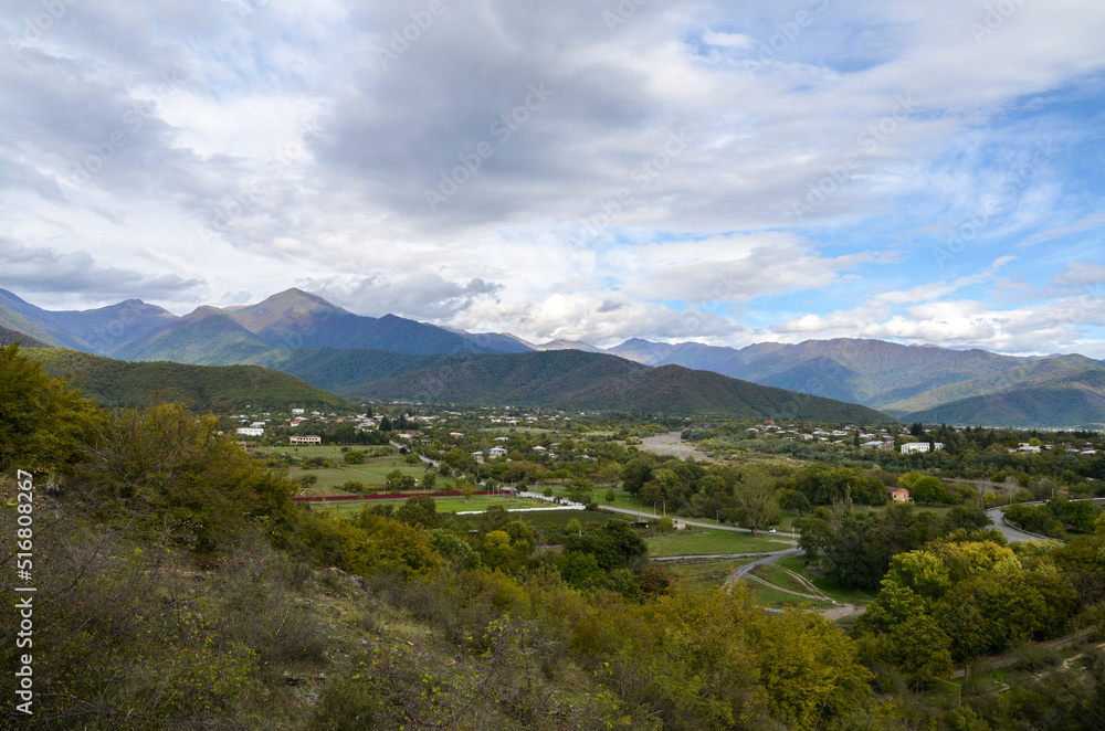 Panoramic view from the height of the hill to the Gremi village in Alazani valley and Caucasian Mountains in the distance. Georgia