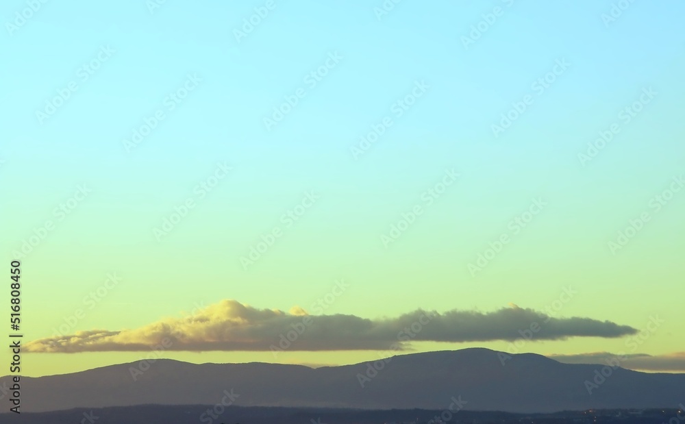 Sierra de Guadarrama vista desde el norte de la ciudad de Madrid, España. Fondo natural donde se puede ver la silueta de las montañas y las nubes con los últimos rayos del sol del día.