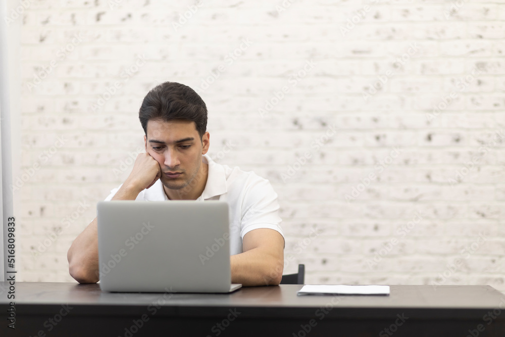 Young serious businessman working on laptop at home. Distant work concept Young serious businessman working on laptop at home. Distant work concept