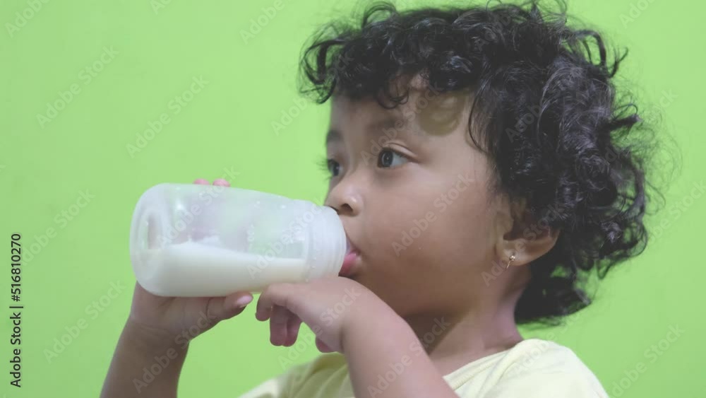 child with curly hair feeding from a bottle, child drinking milk child with curly hair feeding from a bottle, child drinking milk