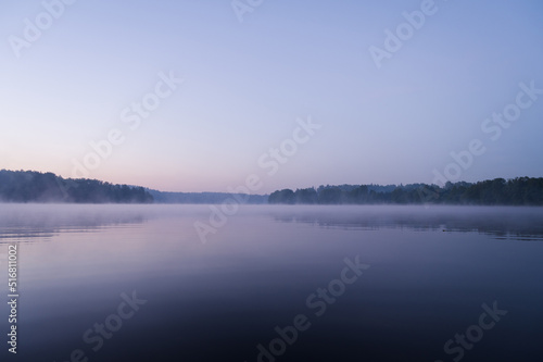 Beautiful mystical landscape. Forest lake at twilight. Fog above calm water. Scenic nature.