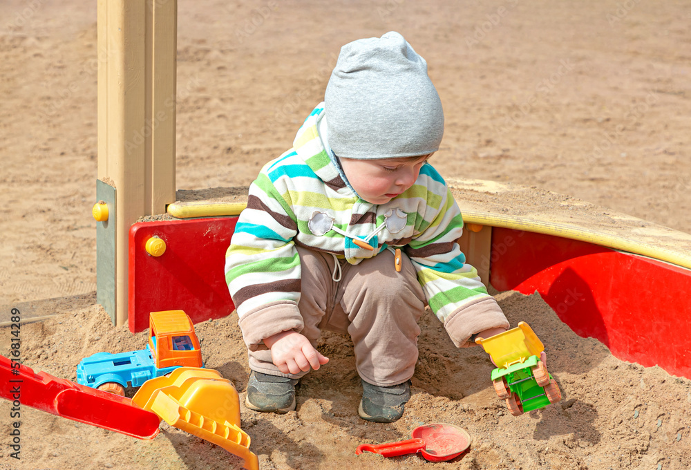 A little boy is playing in a children's sandbox with plastic toys. Kids playing on the playground A little boy is playing in a children's sandbox with plastic toys. Kids playing on the playground