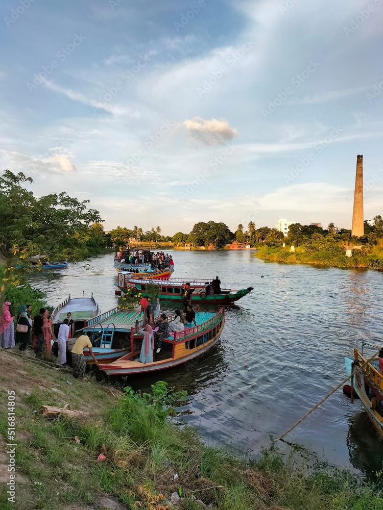 Brick kiln factory riverside. People on the boat in river.