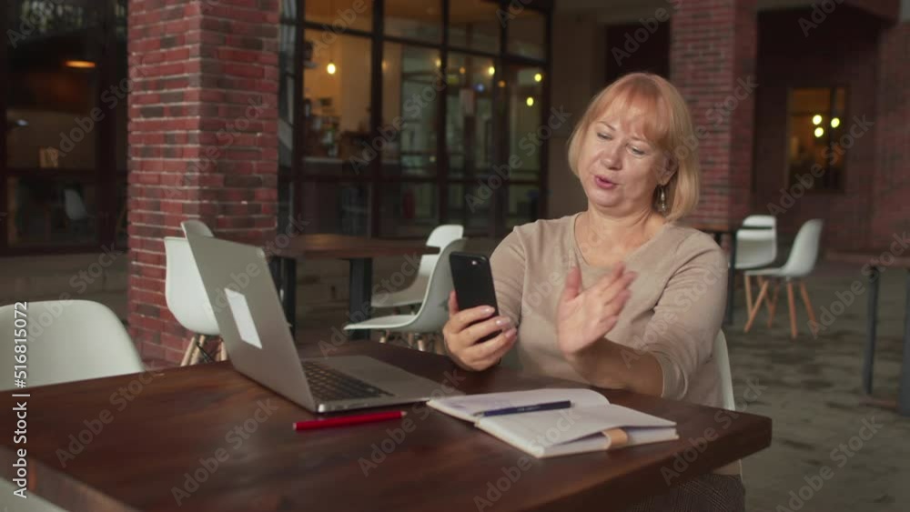 Positive Senior woman having a video call in cafe Positive Senior woman having a video call in cafe