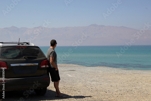 Lonely man stands near car parked at the blue sea. © manowar1973
